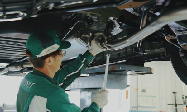 リフトアップされた車の下回りに部品を取り付けている様子