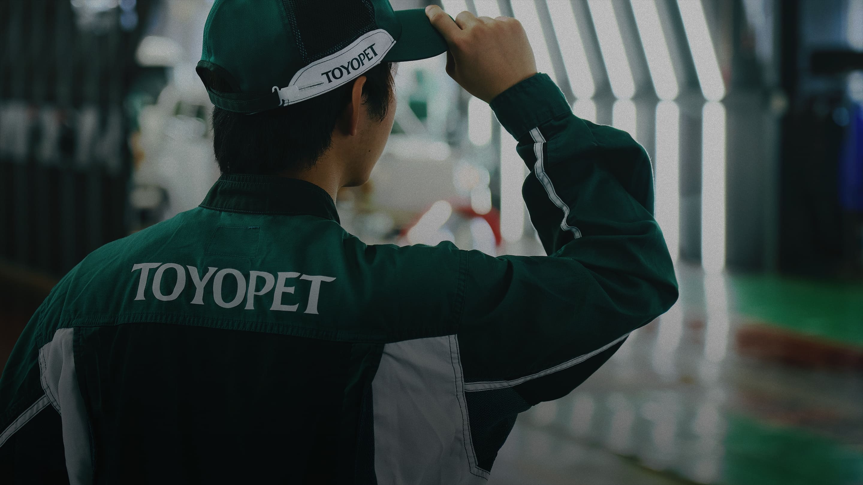 キャップのツバに手を当てた男性メカニックの背中